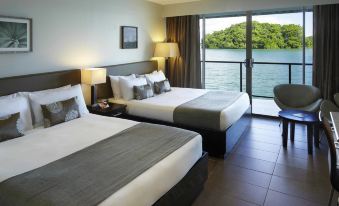 a hotel room with two beds , one on each side of the room , and a balcony overlooking a body of water at Novotel Suva Lami Bay