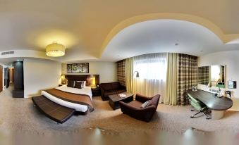 a luxurious hotel room with a large bed , couch , and other furniture , as well as a panoramic view of the room through a at Crowne Plaza Reading East