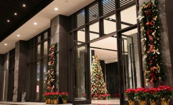 a large christmas tree decorated with red and white lights , standing in front of a building entrance decorated for the holiday season at Platinum Hotel