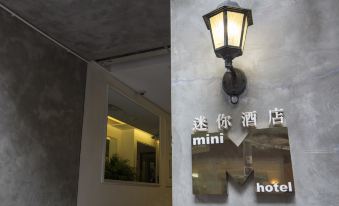 There is a sign on the wall in front of an entrance, illuminated by lights and other lighting fixtures at Mini Hotel Causeway Bay