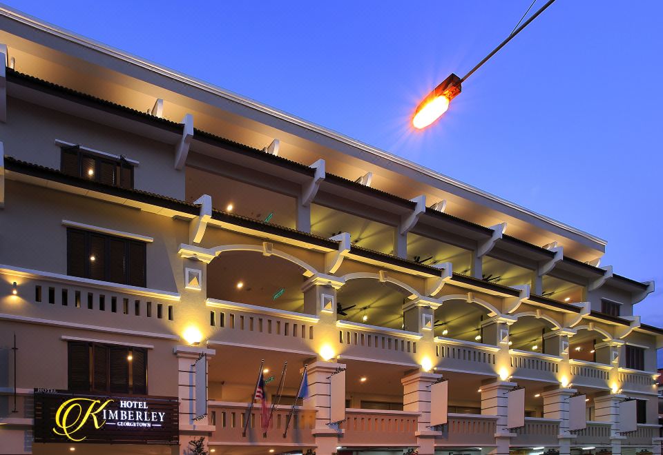 a large , white building with multiple balconies and arches , illuminated by street lights against a dark blue sky at Kimberley Hotel Georgetown