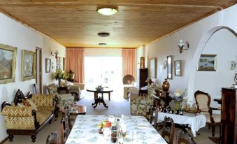 a spacious living room with wooden ceiling , large windows , and a dining area featuring several tables and chairs at Whale Watchers Inn