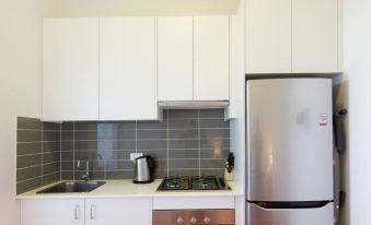 a kitchen with white cabinets , a stainless steel refrigerator , and a black stove top oven at The Star Apartments
