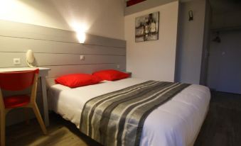 a bed with a white mattress and red pillows is in a room with a headboard and pictures on the wall at Kyriad Lyon Est - Saint Quentin Fallavier