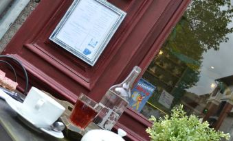 a red door with a framed certificate hanging on it , along with a bottle and a cup of tea at Le Petit Chou