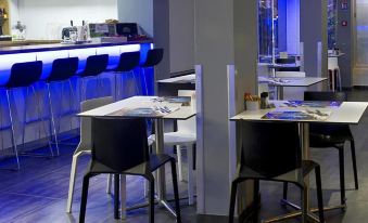 a restaurant with white tables and chairs , a bar , and blue lights in the background at Hotel Beaurivage