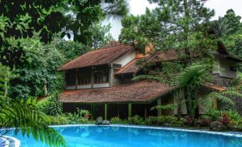 a large house with a red tile roof and a pool in front of it at Imah Seniman