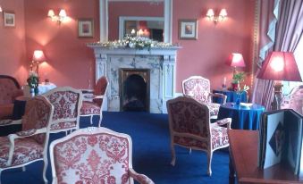 a living room with pink walls , white fireplace , and blue carpet , featuring red and white chairs , blue carpet , and pink walls at Dalmeny Park House Hotel