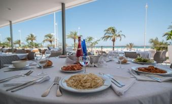 a dining table set with a variety of food , including pasta , wine glasses , and bottles at RH Bayren Hotel & Spa