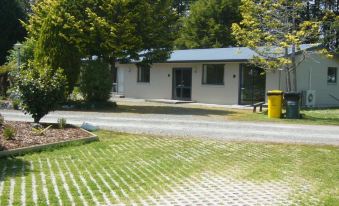 a small white house surrounded by trees , with a paved walkway leading up to the front door at All Seasons Holiday Park