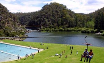 a group of people enjoying a day at a park by a lake , with some of them riding a water slide at Aspect Tamar Valley Resort
