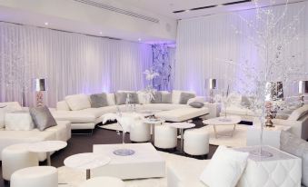 a large white room with a couch , chairs , and tables is decorated with purple lights at Alpha Hotel Eastern Creek
