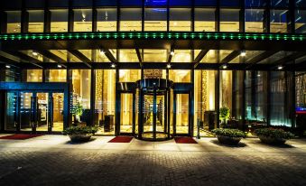 The illuminated entrance of a hotel at night provides a view of the outside through its glass windows at Paramount Gallery Hotel