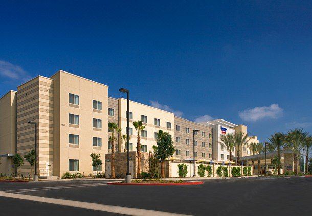 a holiday inn express hotel with its white exterior and palm trees in the foreground at Fairfield Inn & Suites by Marriott Tustin Orange County