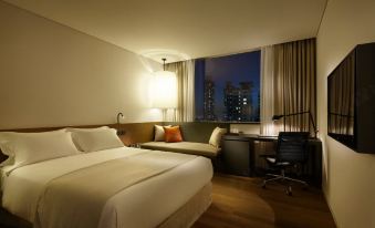 a modern hotel room with a large bed , white bedding , and a view of the city at night at Shilla Stay Dongtan
