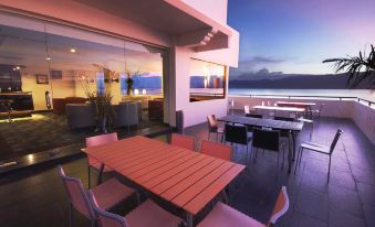 a modern outdoor patio with a dining table , chairs , and a view of the ocean at Swiss-Belhotel Silae Palu