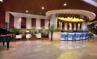 a large , well - lit hotel lobby with a bar and several seating areas , including couches and chairs at Atria Hotel Malang