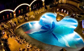 a large pool with a blue flower design is surrounded by tables and chairs in an outdoor setting at Loisir Hotel Naha