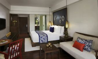 a hotel room with a king - sized bed , a couch , and a tv . the room is clean and well - organized at Anantara Hua Hin Resort